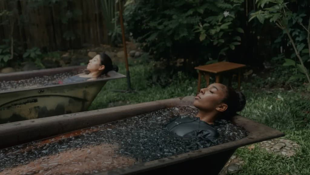 Two women in ice baths in a garden setting